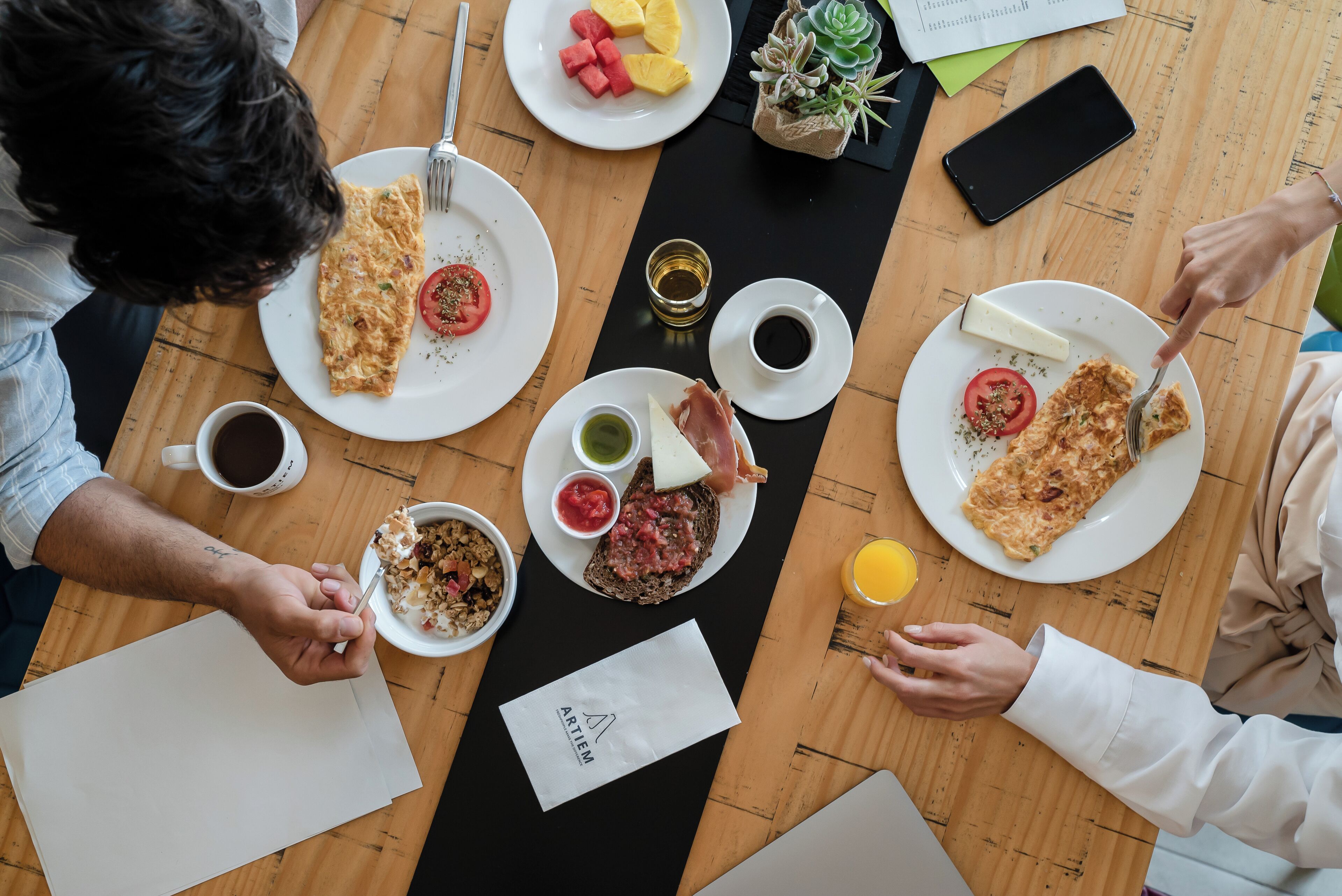 A wooden table with breakfast items including toast, fruit, and coffee.