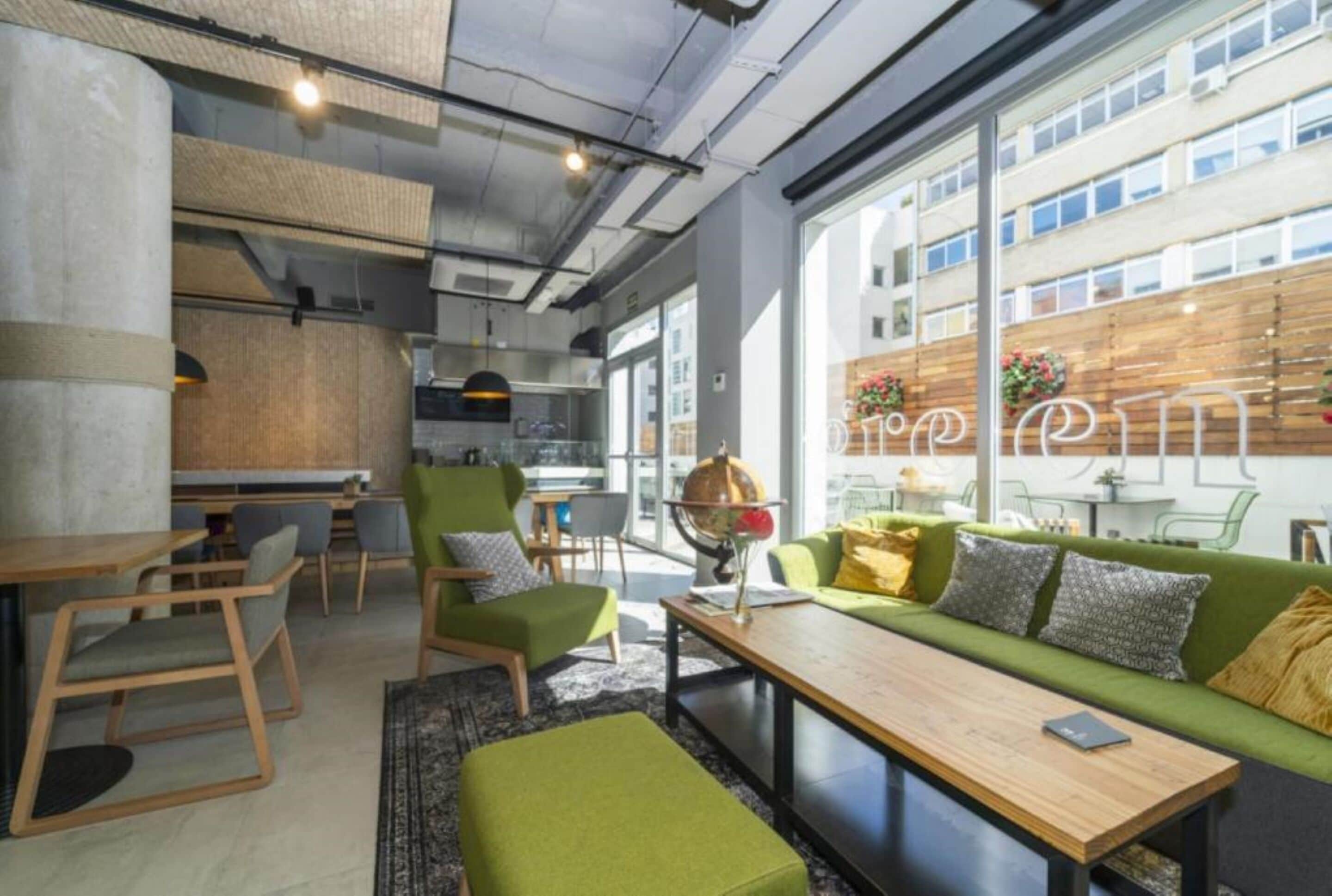 Un intérieur moderne avec un canapé vert, des tables et des chaises en bois.
