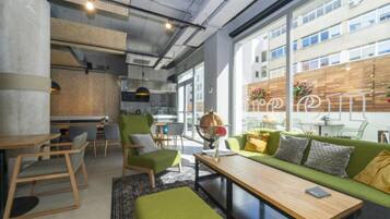 Un intérieur moderne avec un canapé vert, des tables et des chaises en bois.