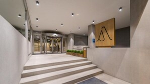 A modern hotel lobby with a staircase leading to a revolving door, a reception desk, and a wooden accent wall. - ARTIEM Madrid Hotel (Madrid)