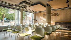A conference room with white chairs and a large pillar, a wooden wall with the number 610, and a sign that reads "OPEN MIND, DIFFERENT". - ARTIEM Madrid Hotel (Madrid)