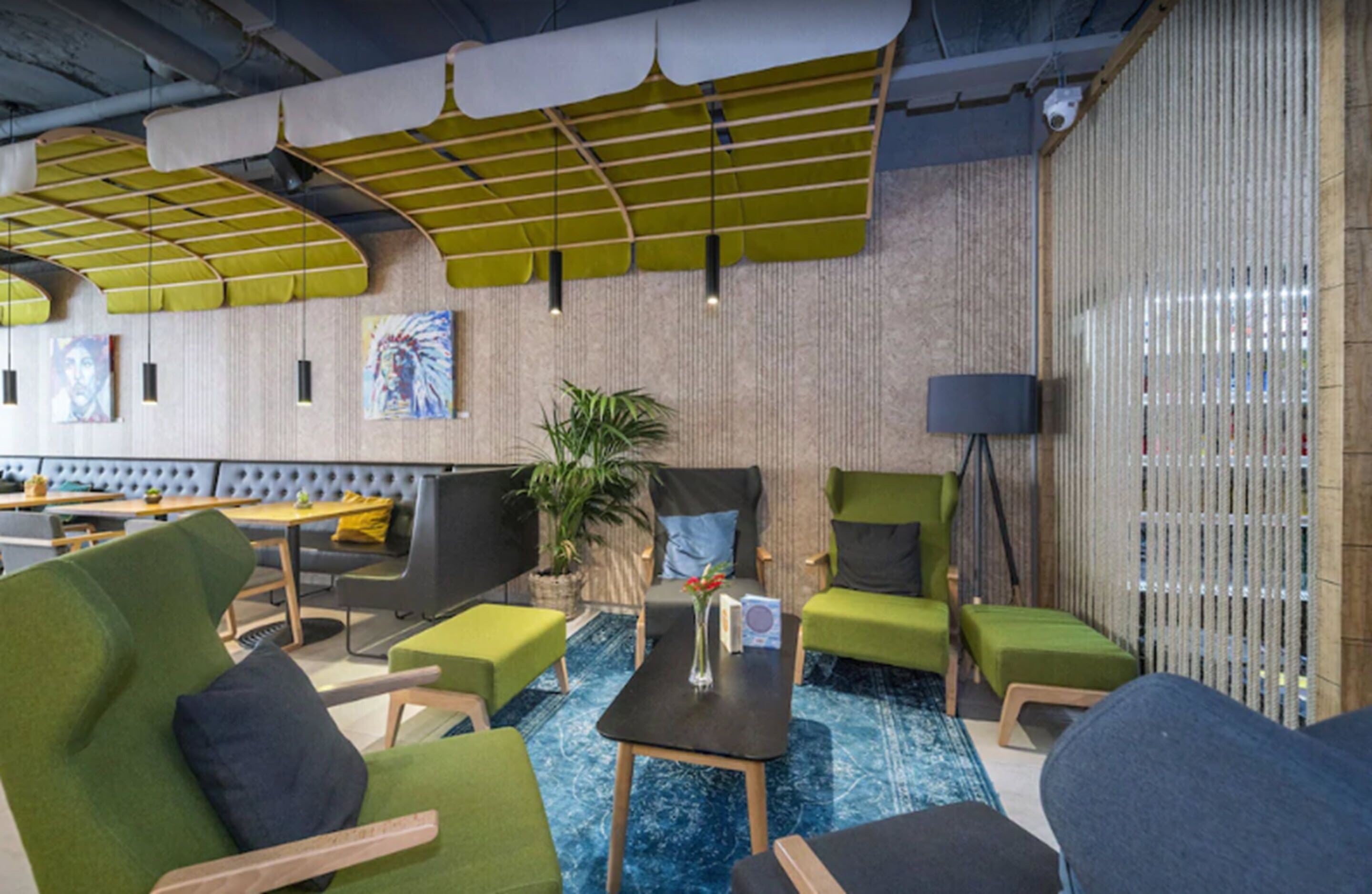 A modern lounge area with green upholstered seating, a coffee table, and a potted plant.