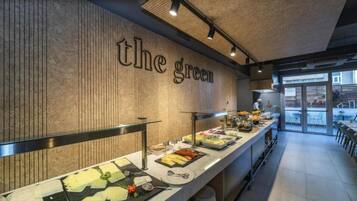 Zona de bufé con diversos alimentos y una pared con el texto 'the green'.