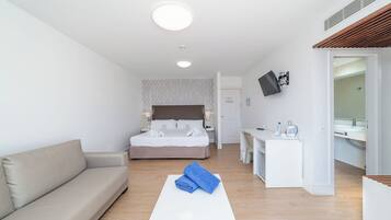 A hotel room with a bed, a sofa, a desk, and a bathroom.