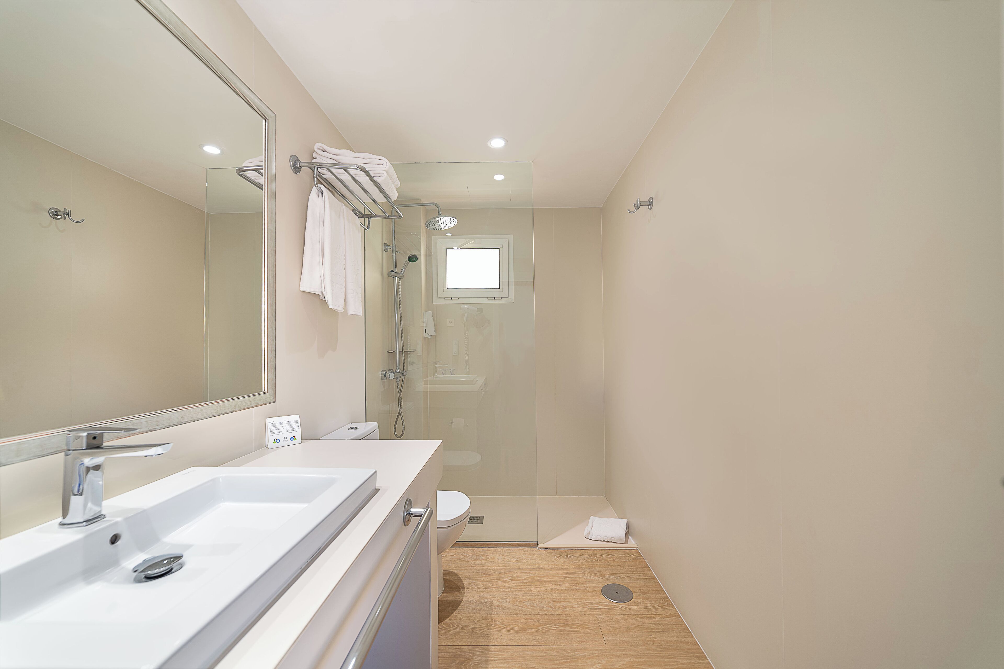 Un baño moderno con un espejo grande, un lavabo, una ducha y un inodoro.