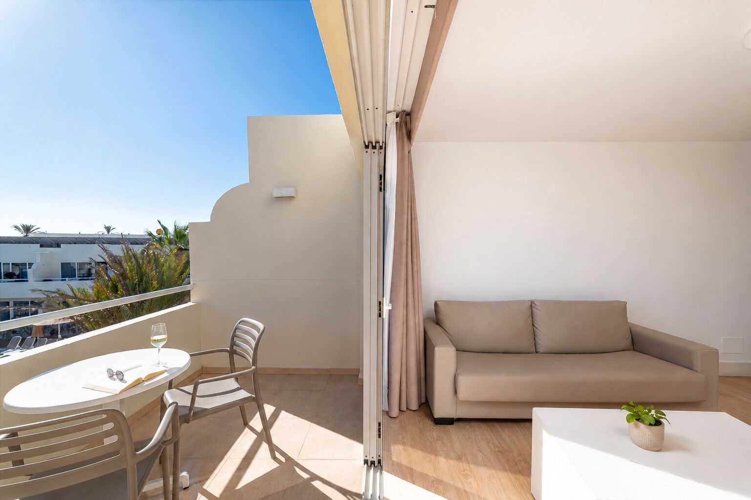 Un balcon avec une table, des chaises, un canapé et une plante en pot.