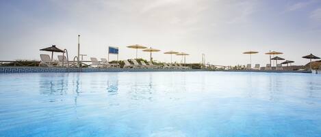 A swimming pool with lounge chairs and umbrellas.