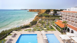 Een resort met twee zwembaden, toegang tot het strand en uitzicht op de oceaan en kliffen.