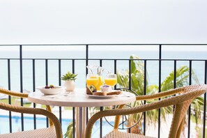 A round table with breakfast items and drinks, overlooking a pool and palm trees. - Hipotels Hotel Flamenco Conil (Conil de la Frontera)