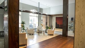 A modern lobby with a wooden floor, a glass coffee table, and white armchairs. - Gran Hotel Albacete (Albacete)