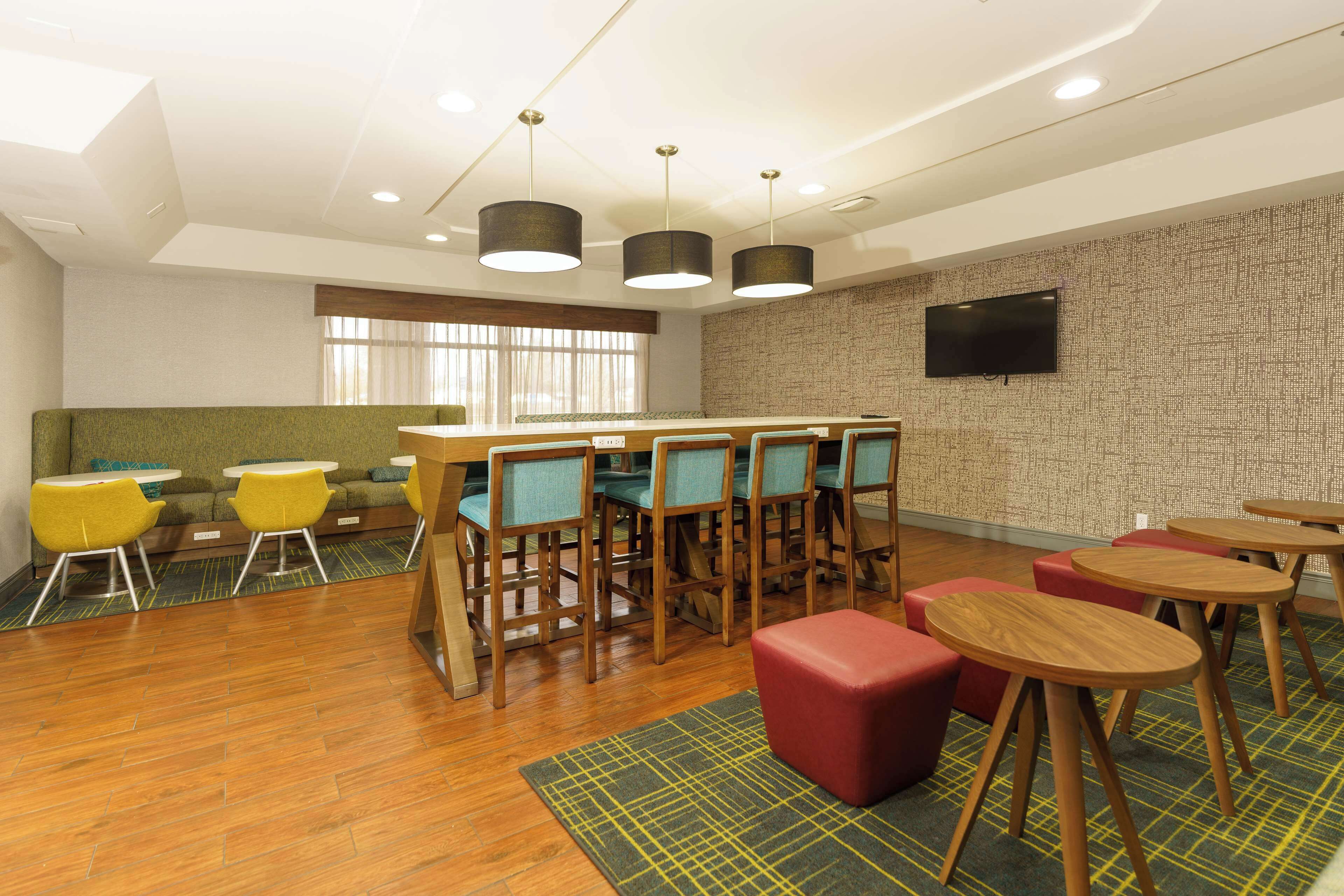 A modern lounge area with wooden tables, chairs, and a bar counter.