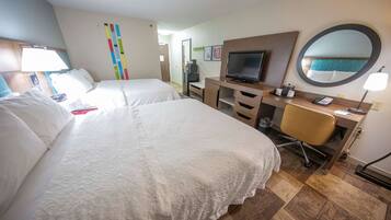 Habitación de hotel con dos camas, un escritorio con computadora y teléfono, una silla y una televisión.