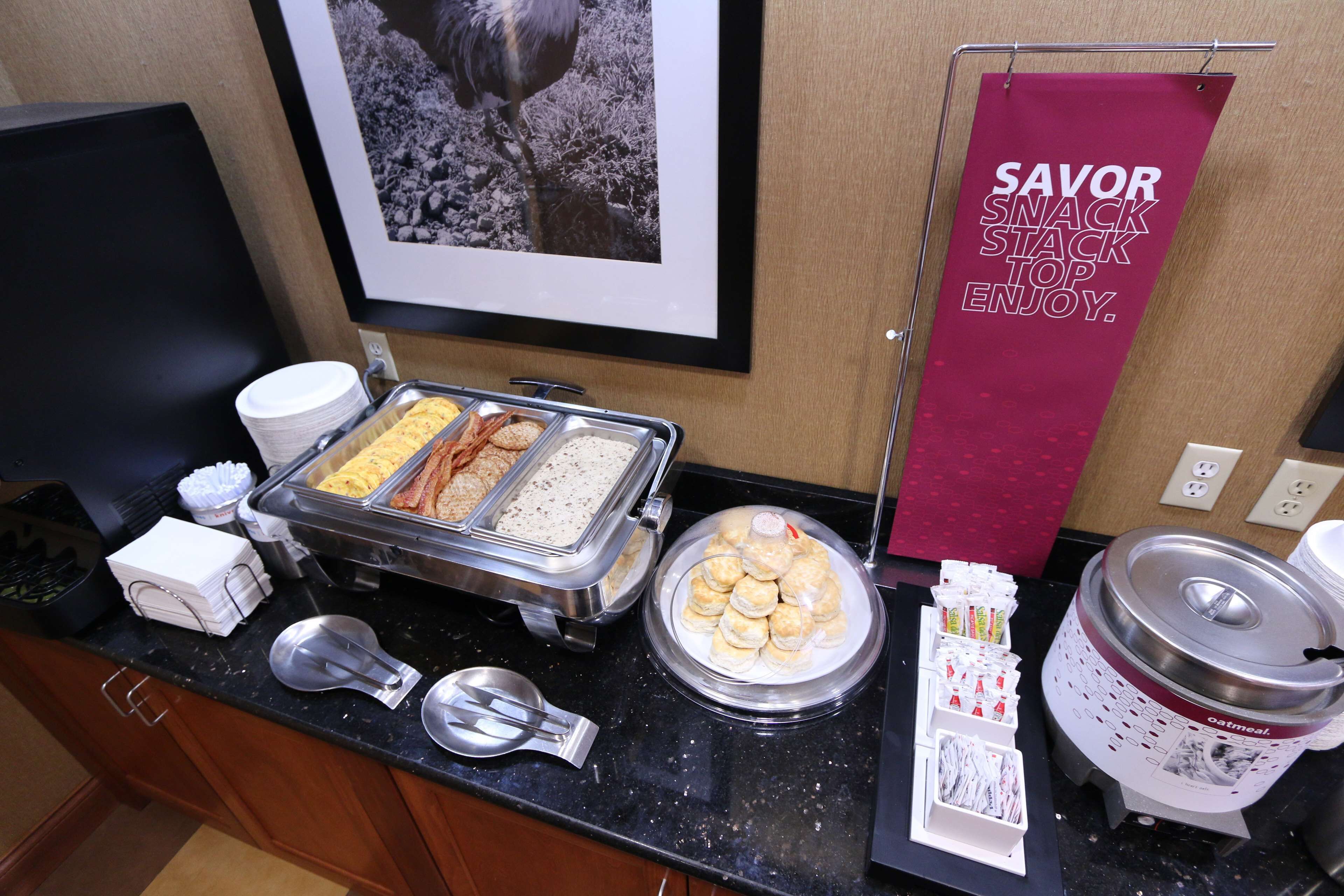 A buffet setup with various food items, a sign promoting snacks, and a coffee machine.