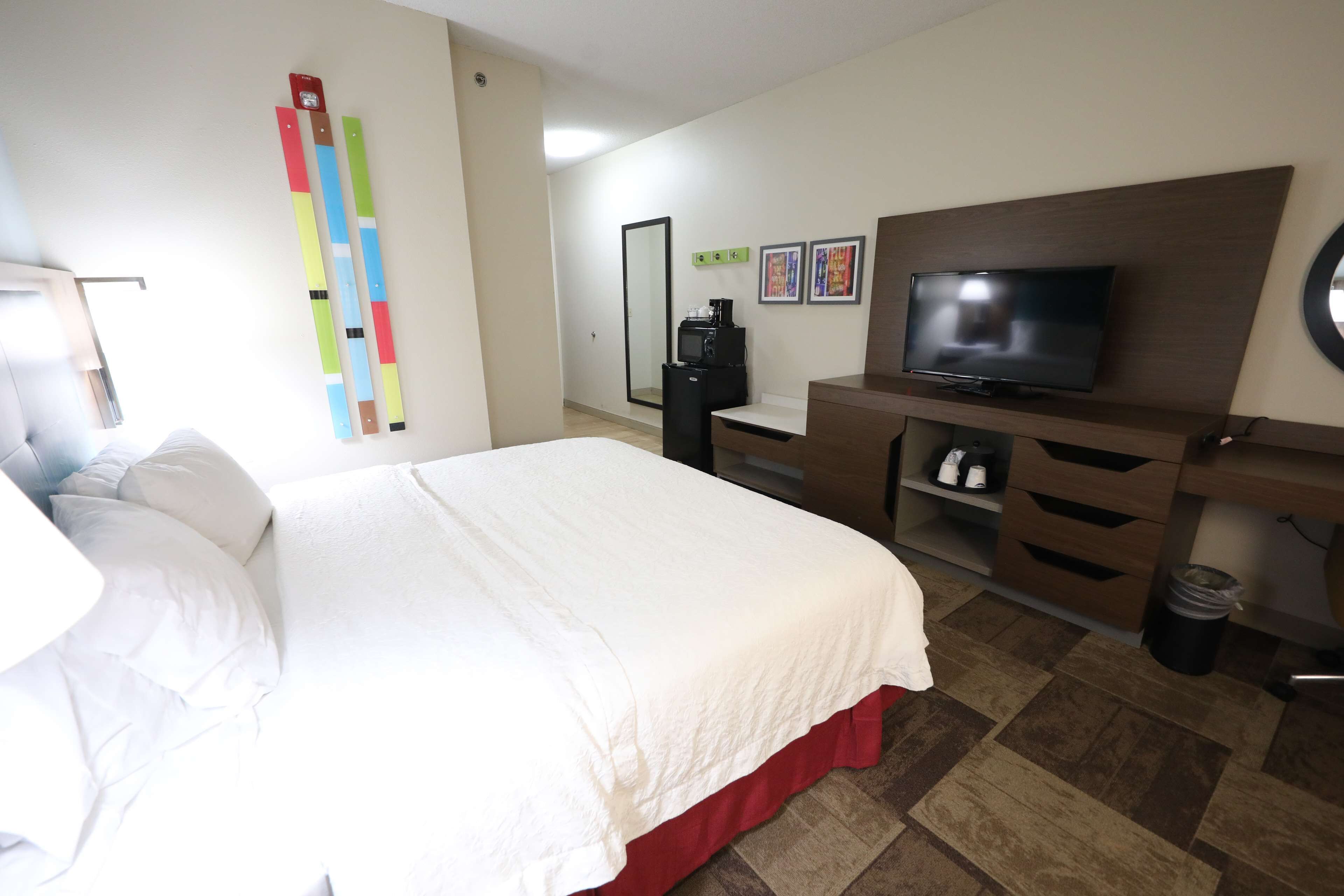 Une chambre d’hôtel avec un lit, une télévision, un bureau et un miroir.