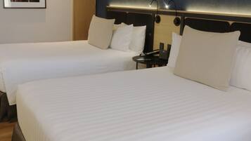 Habitación de hotel con dos camas, una mesita de noche, un cuadro en la pared y una revista sobre la cama.