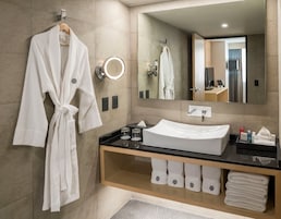 Une salle de bain moderne avec un grand miroir, un lavabo blanc et un peignoir suspendu à un porte-serviettes.