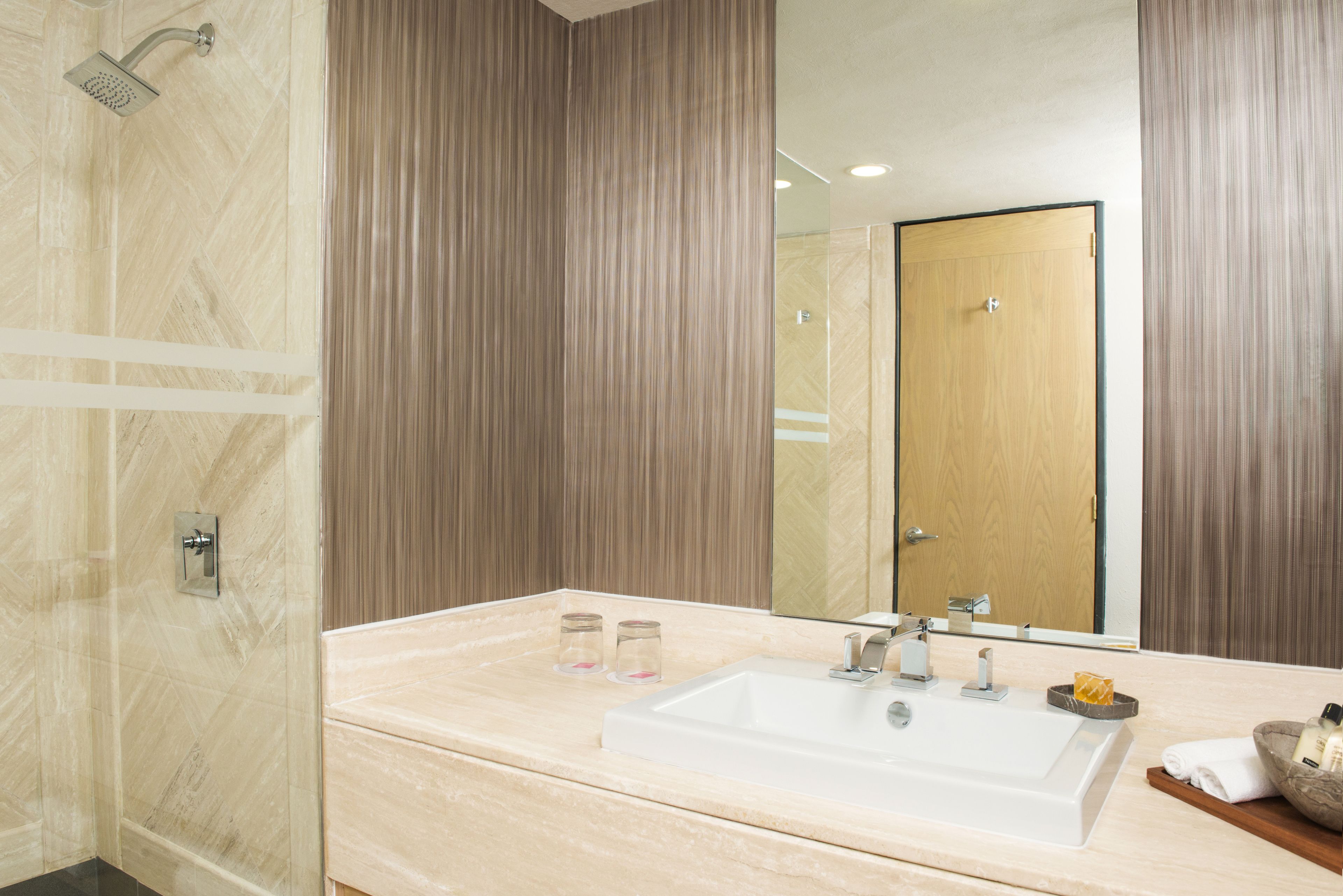 A modern bathroom with a large sink, mirror, and shower.