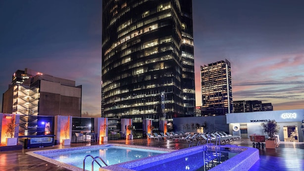 A rooftop pool area with lounge chairs and a yoga studio.