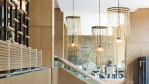 A modern interior with wooden paneling, a glass staircase, and pendant lighting.
