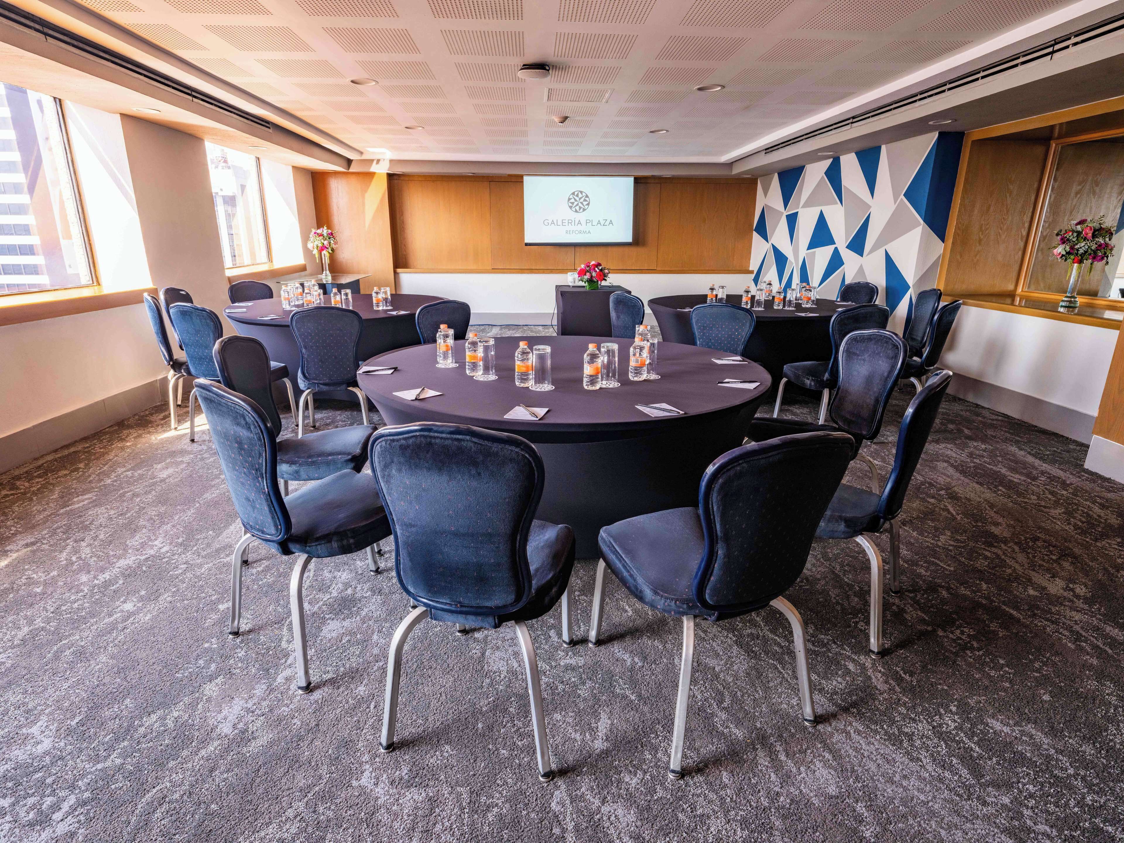 A conference room with round tables, chairs, and a projector screen displaying "Galleria Azzo".
