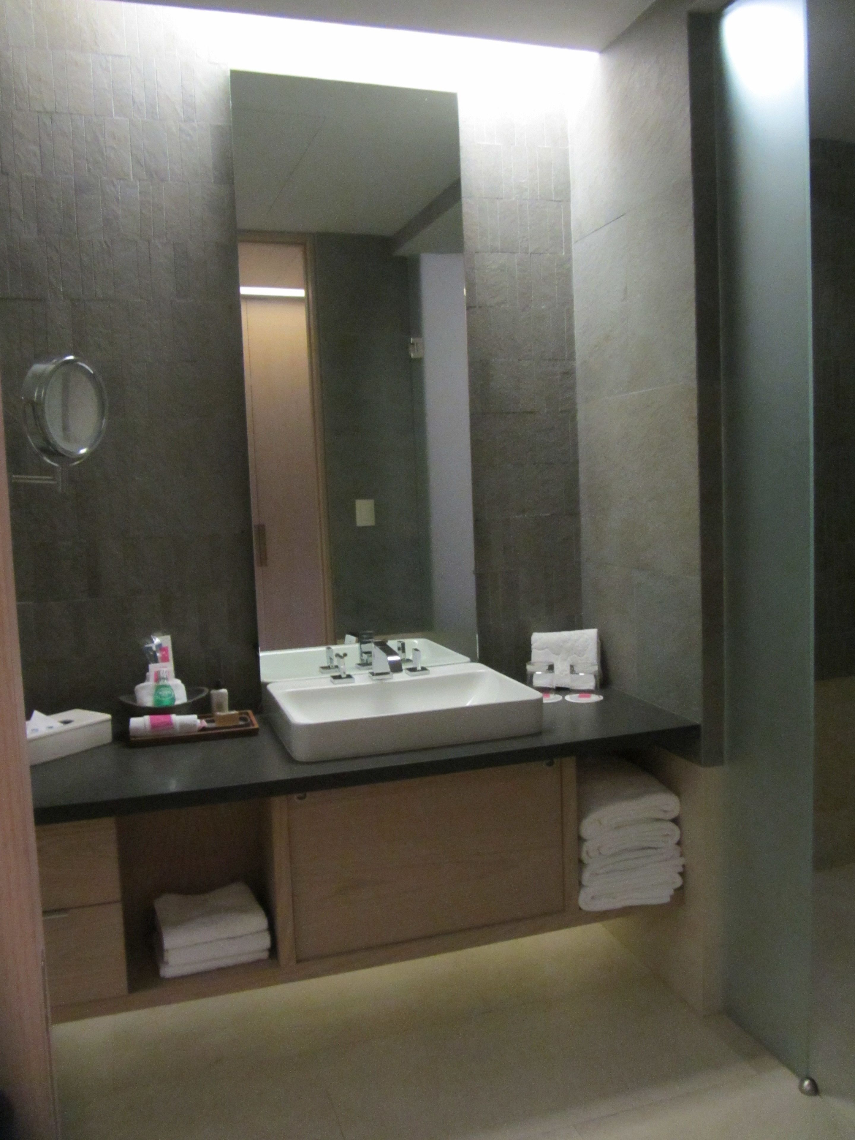 A modern bathroom with a large mirror, a white sink, and a towel rack.