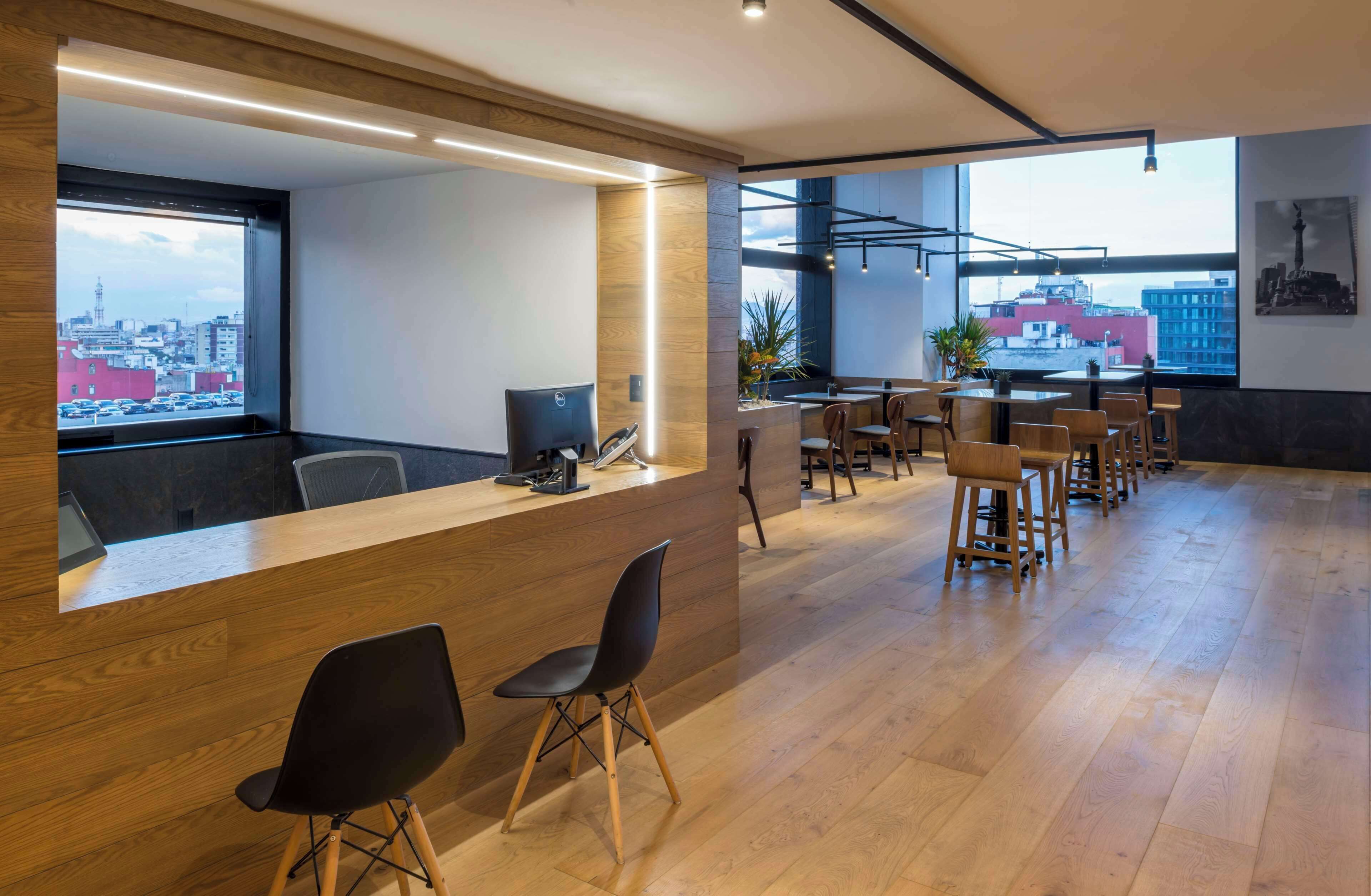 A modern office space with a reception desk, multiple seating areas, and large windows offering city views.