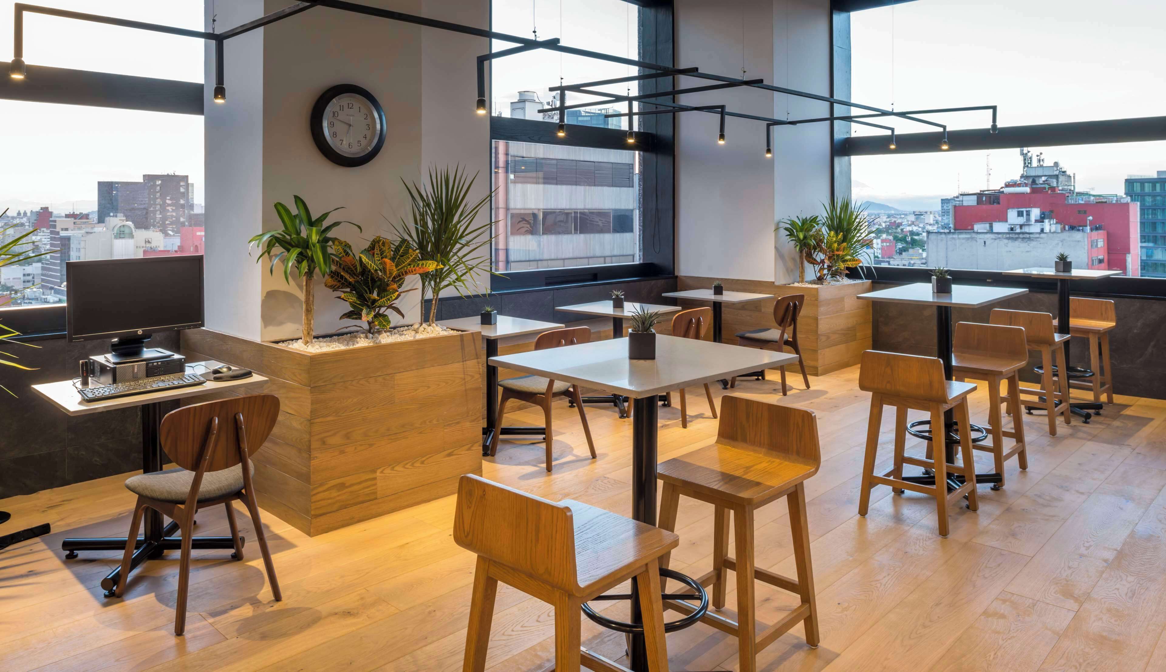 Un café moderne avec des meubles en bois, une horloge au mur et de grandes fenêtres donnant sur la ville.