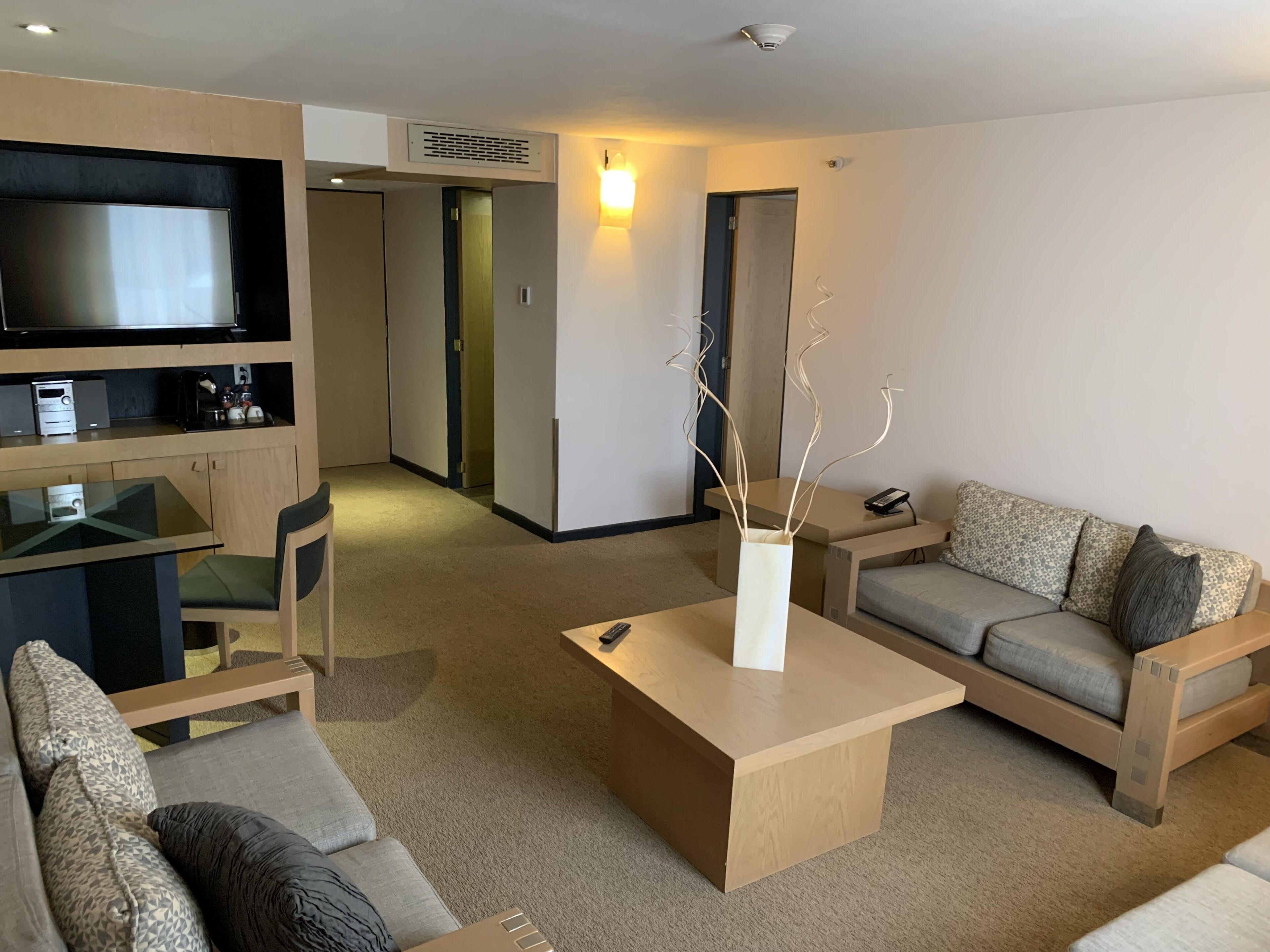 Uma sala de estar moderna com uma televisão de tela plana, uma mesa de centro de madeira e um sofá.