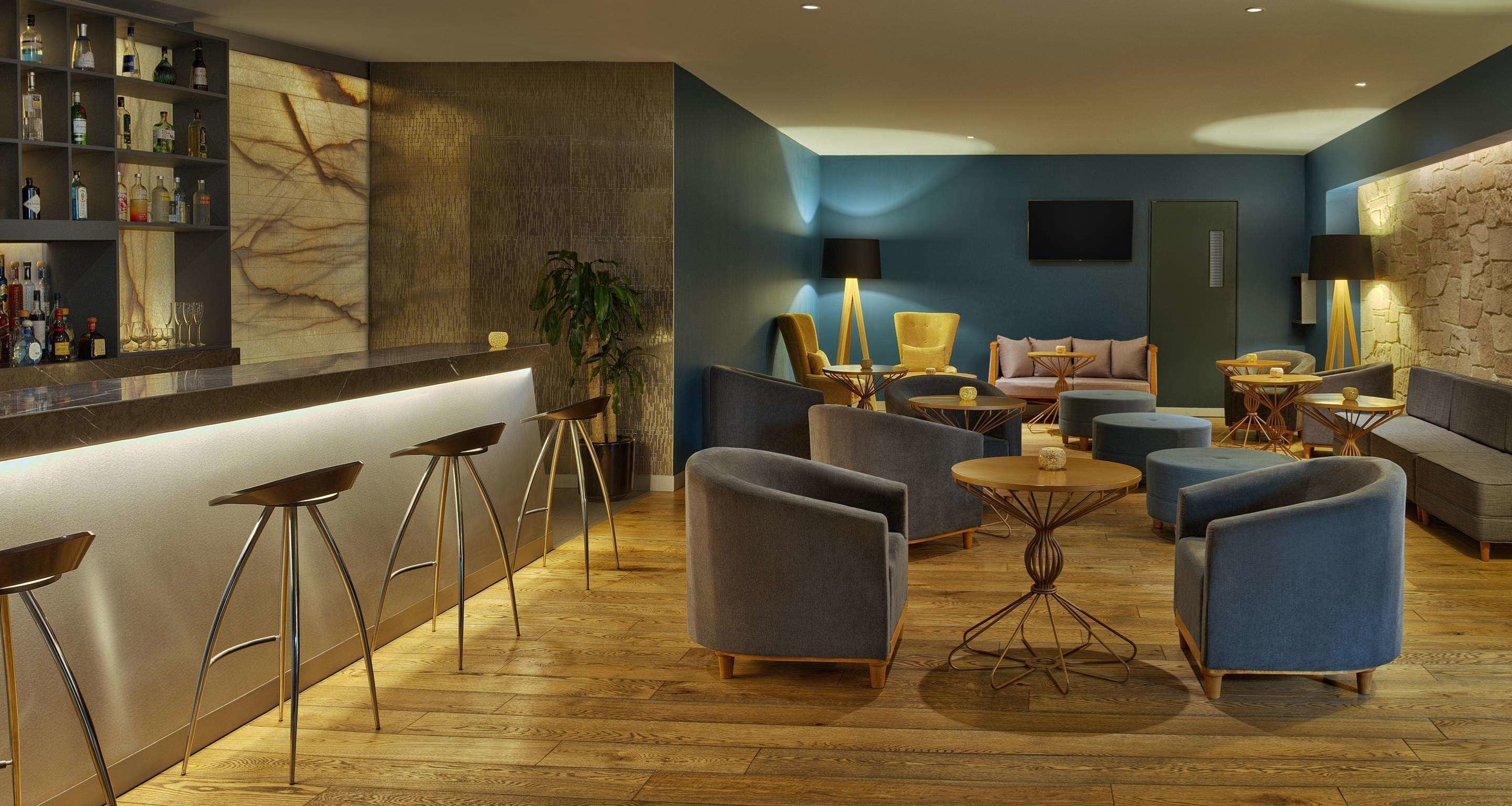 Een moderne lounge met barstoelen, banken en een ronde tafel.