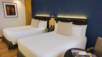 A hotel room with two beds, a nightstand, and a magazine on the table.
