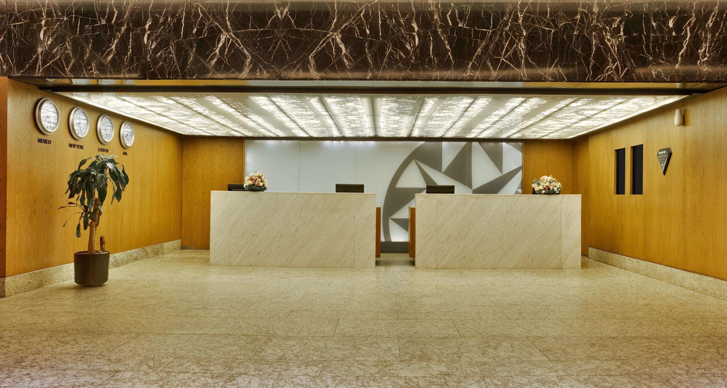 Eine Lobby mit Marmorböden, einem Empfangstresen, einer Pflanze und einer Wanduhr.