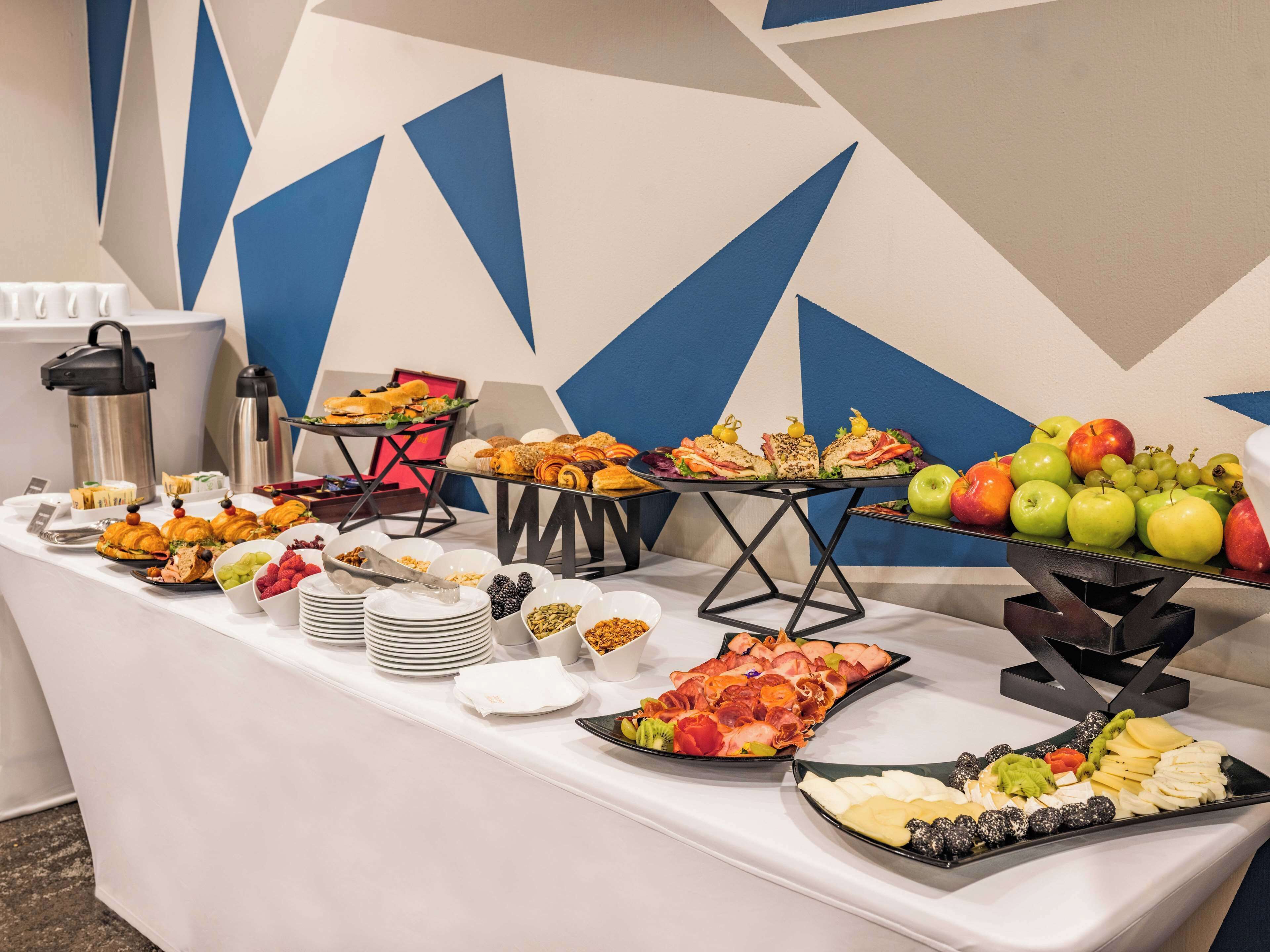 A buffet table with various food items including sandwiches, fruits, and cheeses.