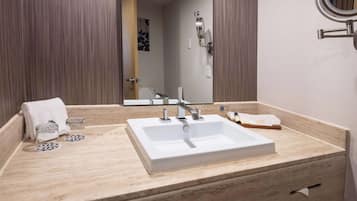 Un bagno con un lavandino bianco, uno specchio e un portascopevoli.