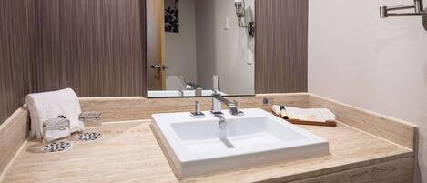 A bathroom with a white sink, a mirror, and a towel rack.