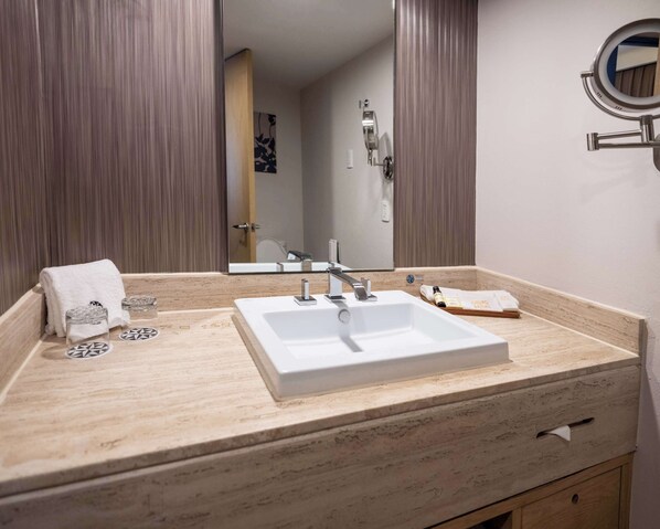 A bathroom with a white sink, a mirror, and a towel rack.