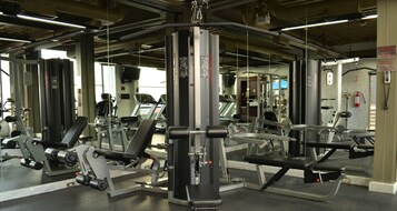 Una palestra con diverse macchine per esercizi, specchi e un estintore a parete.