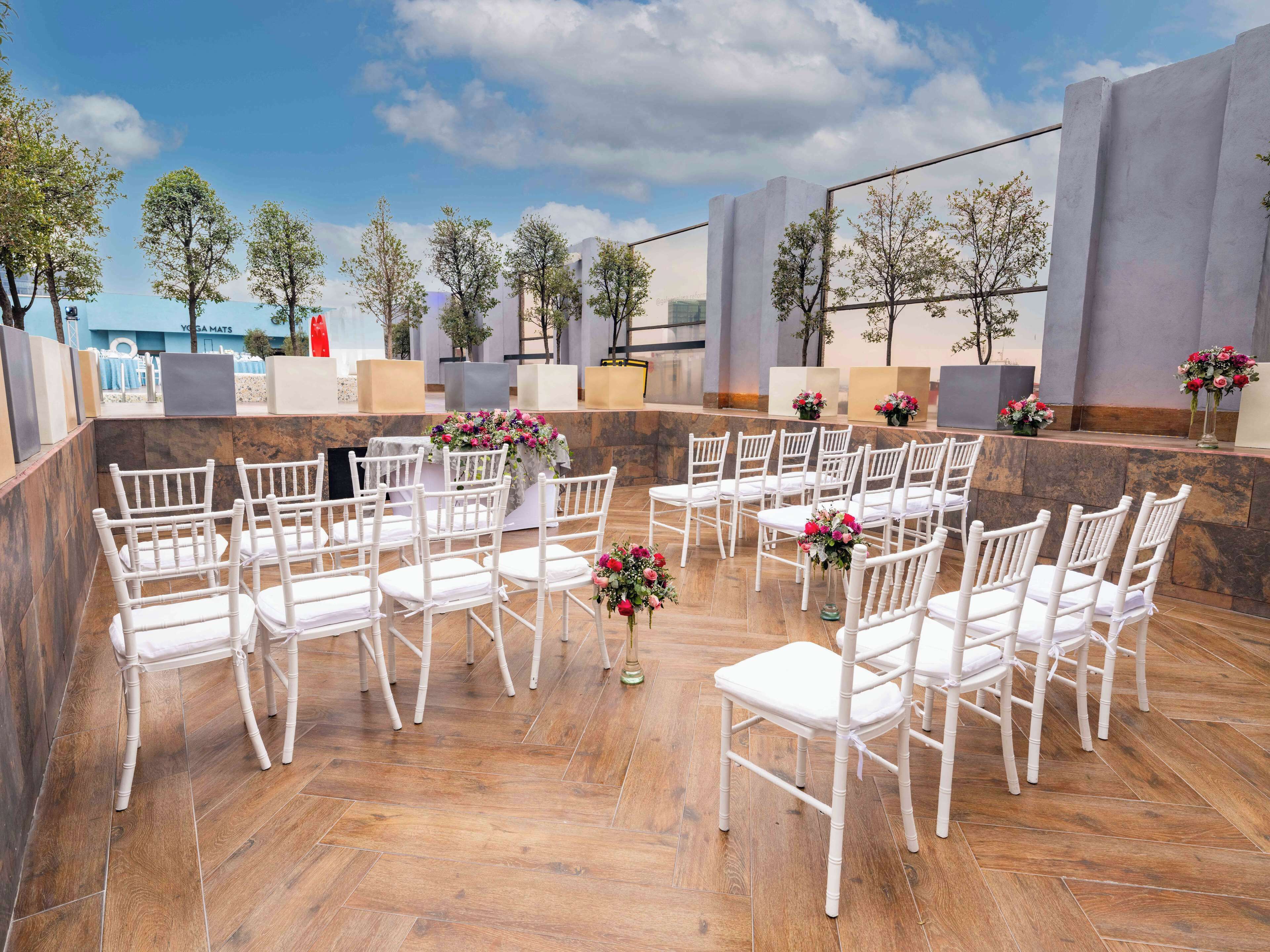 An outdoor seating area with white chairs and tables, arranged in a semi-circle.