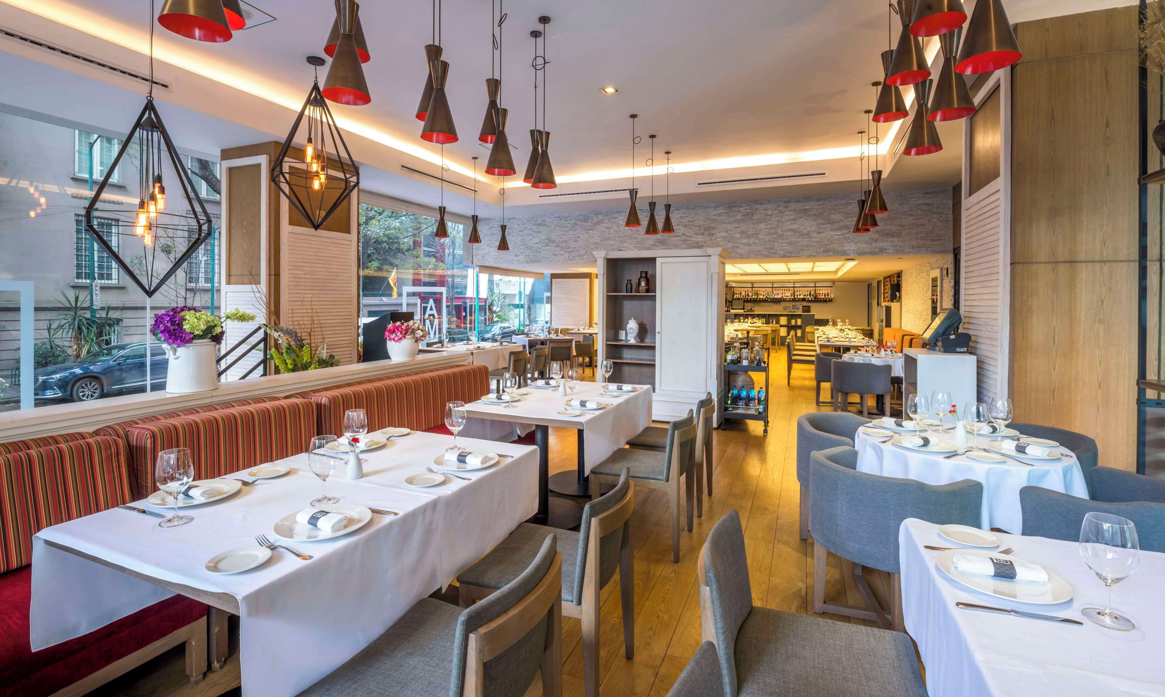 A restaurant with multiple dining areas, including a bar and a seating area with a view of the street.
