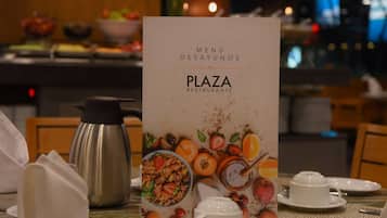 Um cenário de café da manhã com um quadro de cardápio, cafeteira, bule de chá e itens para o café da manhã sobre a mesa.