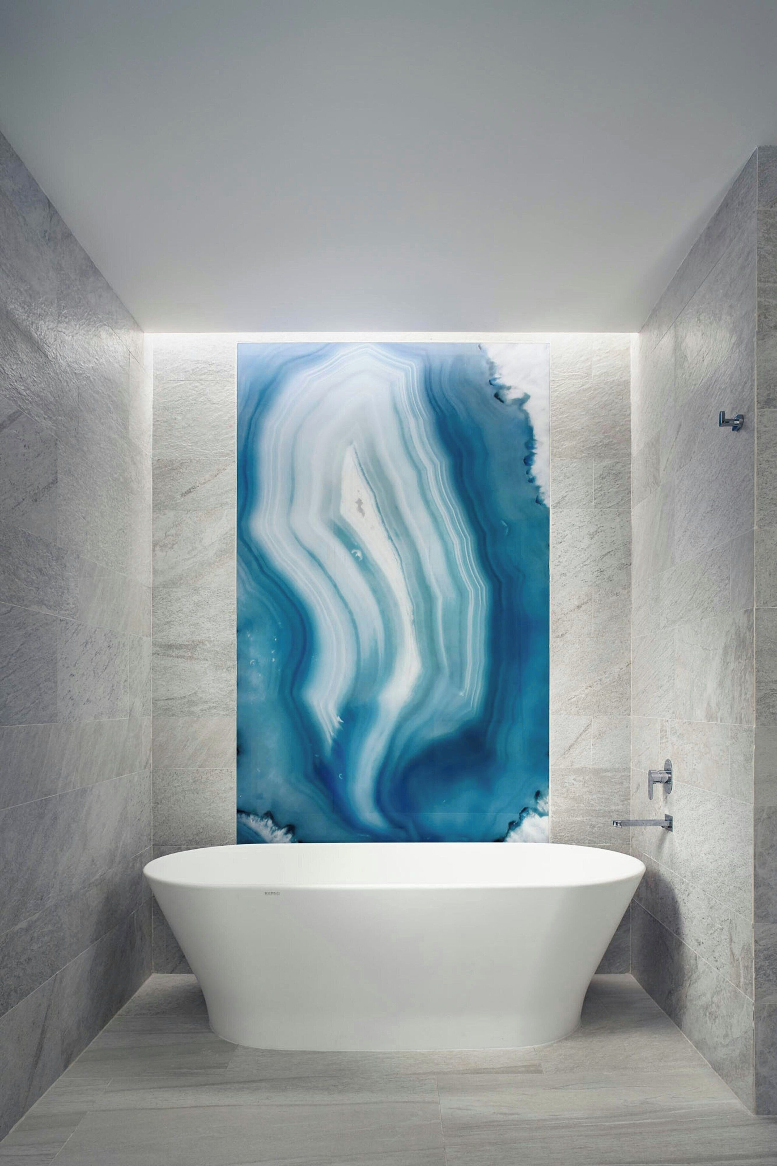 A modern bathroom with a freestanding bathtub, marble walls, and a large abstract blue artwork above the tub.