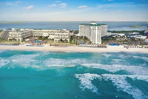 Un hotel costero con varias construcciones, frente a la playa y vistas al océano.