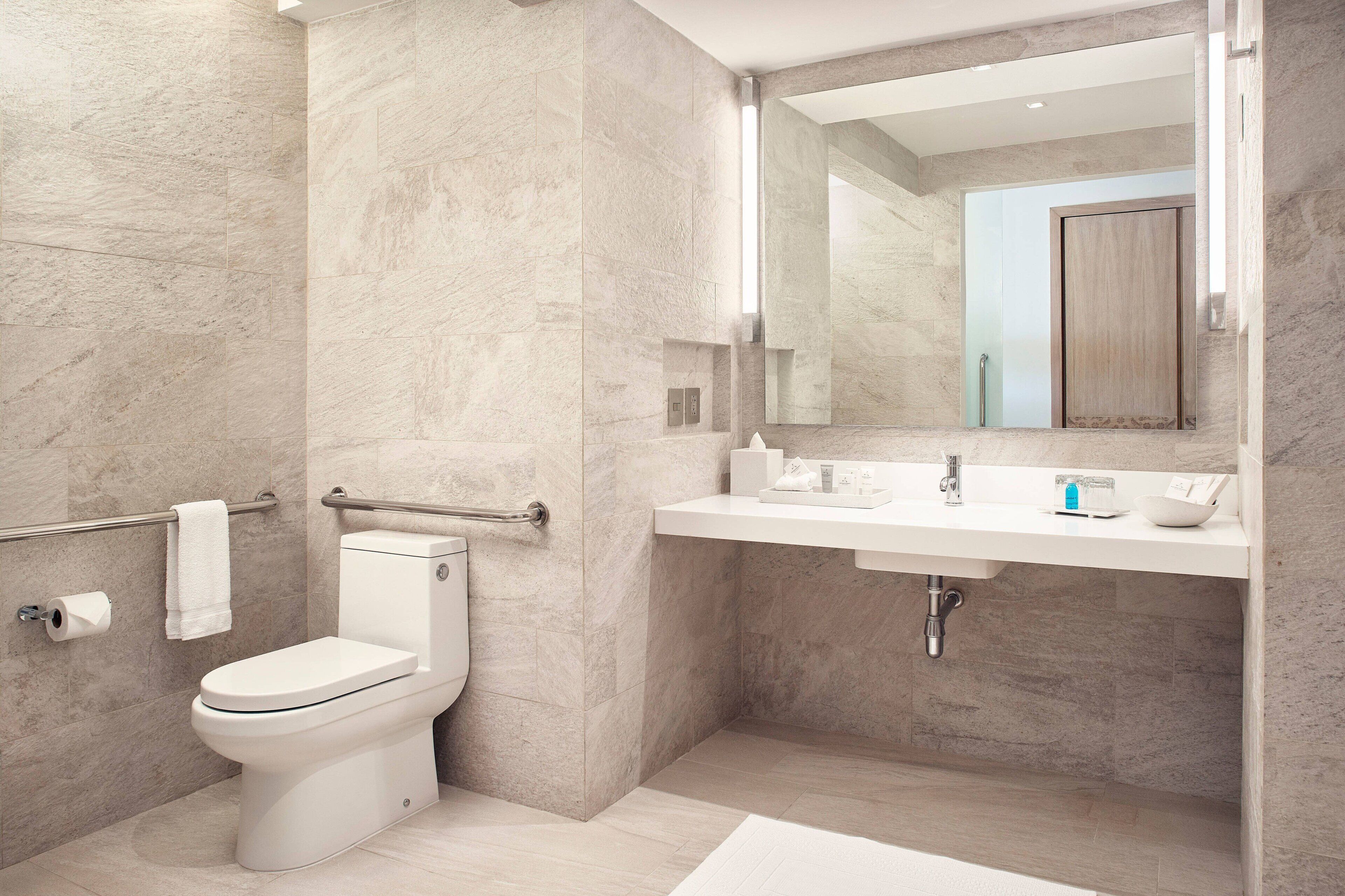 A modern bathroom with a toilet, sink, and mirror.