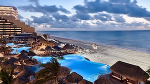 Un resort con piscina, playa y bungalows sobre el agua.