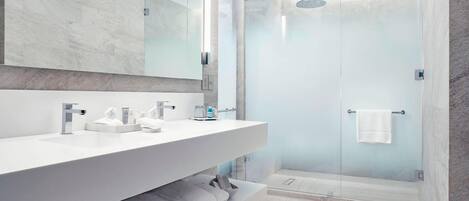 A modern bathroom with a large mirror, two sinks, and a glass-enclosed shower.