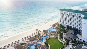 Un resort con un amplio espacio de piscina, playa y vistas al océano.