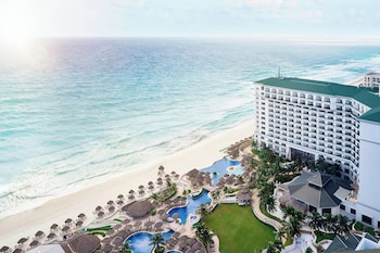 A resort with a swimming pool, beach, and overwater bungalows. at JW Marriott Cancun Resort & Spa