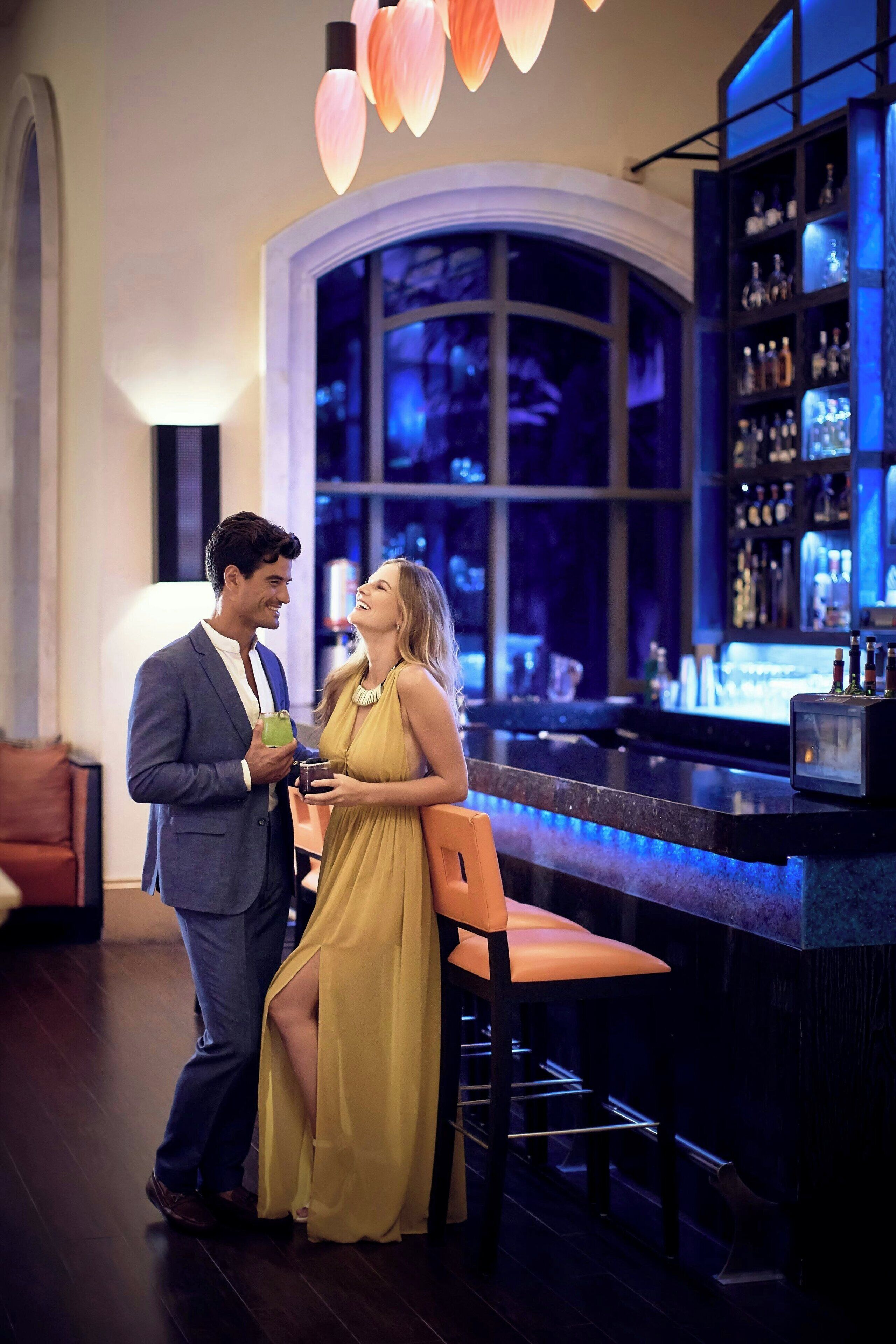 A bar area with a large window, a bar counter, and shelves with bottles.