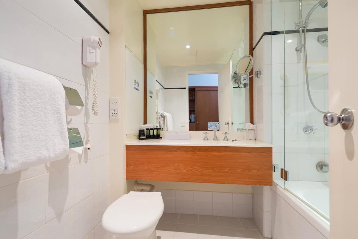 A modern bathroom with a wooden vanity, a glass shower enclosure, and a white toilet.