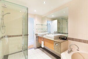 Un baño moderno con ducha de vidrio, lavamanos dobles y un espejo grande.