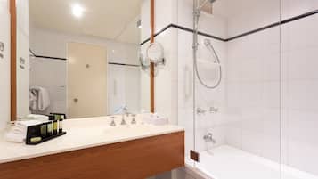 A modern bathroom with a wooden vanity, a glass shower enclosure, and a white bathtub.
